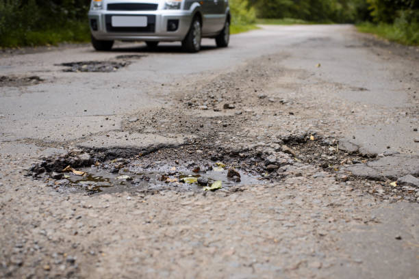 istock Damaged asphalt pavement road with many big and deep potholes. 1272787685
