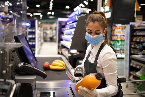 Cajero en supermercado con máscara y guantes totalmente protegidos contra el virus corona. Trabajar durante la pandemia de covid-19. photo