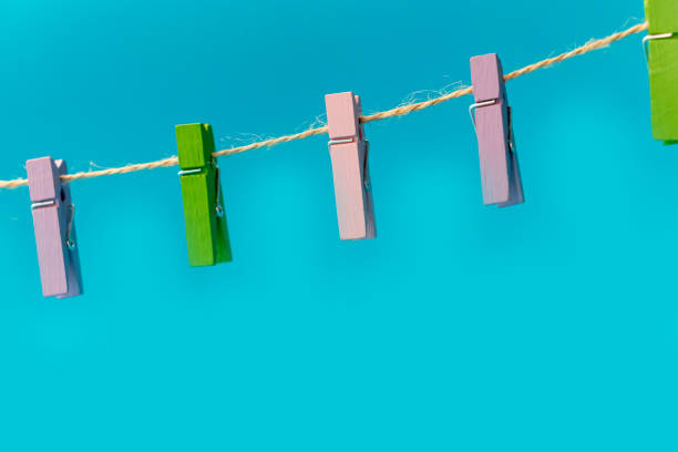 istock Multicolored wooden clothespins on a rope isolated on blue background 1272789300