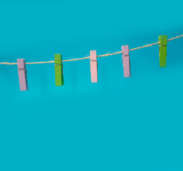 istock Multicolored wooden clothespins on a rope isolated on blue background 1272789305