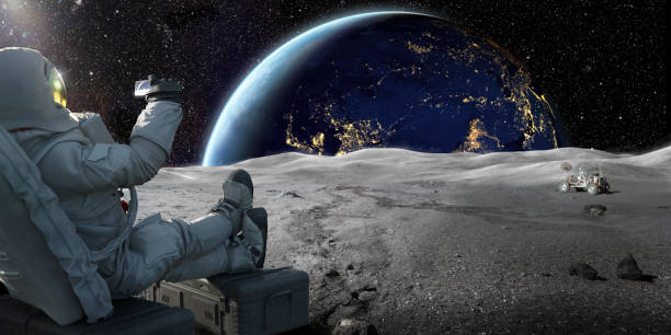 Astronaut Sitting On Moon Recording Sunrise On Earth With Smartphone An astronaut sitting on a crate on the lunar surface, holding up a smartphone recording the sun as it starts to rise over the earth. 

Credit: Earth image from NASA https://earthobservatory.nasa.gov/images/79790/city-lights-of-asia-and-australia space exploration photos stock pictures, royalty-free photos & images