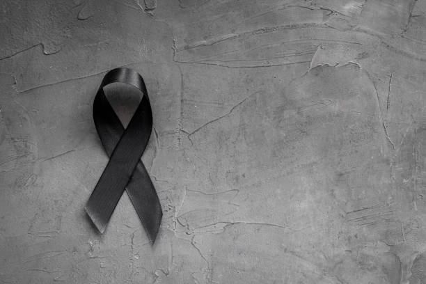 istock Black awareness ribbon on dark background. Mourning symbol 1272795557