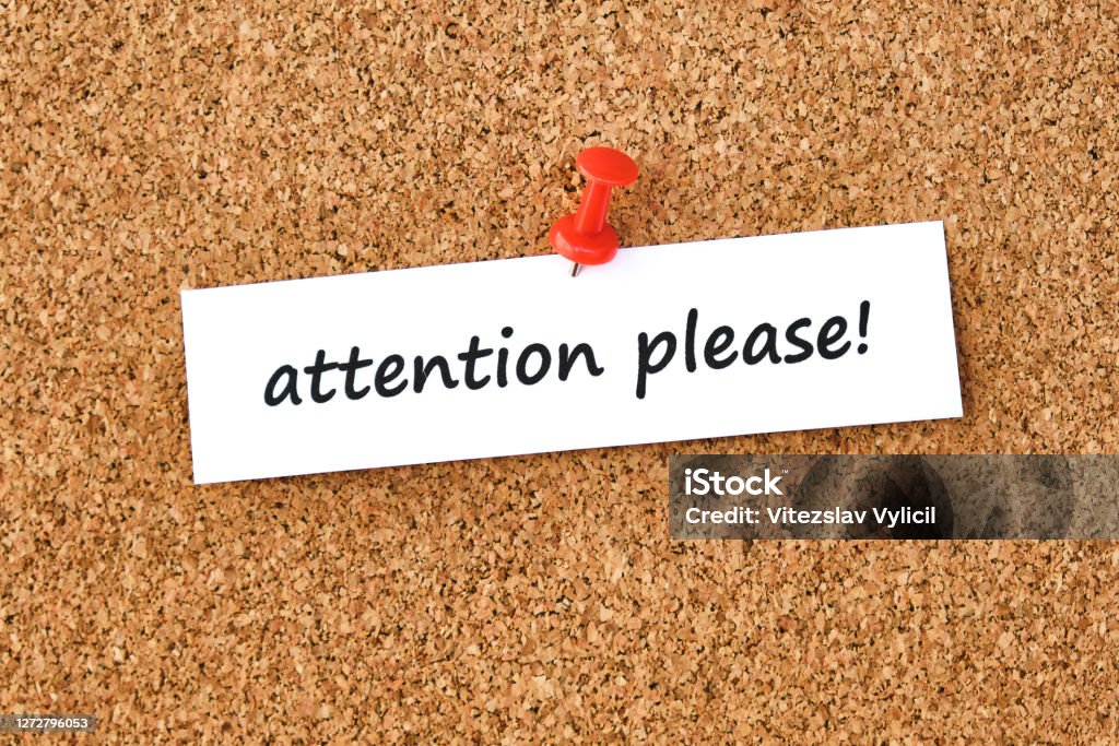 Attention please. Text written on a piece of paper, cork board background. Attention please. Text written on a piece of paper or note, cork board background. Concentration Stock Photo