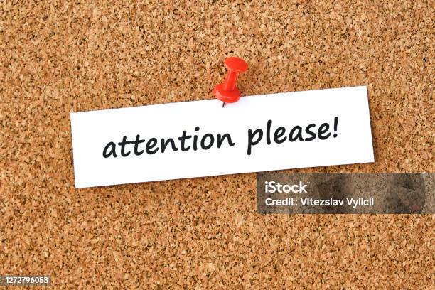 Attention Please Text Written On A Piece Of Paper Cork Board Background Stock Photo - Download Image Now