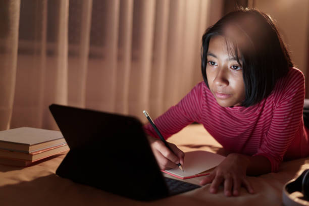 istock Asian girl is studying online via the internet on tablet while lying on the bed and doing homework in the night. Concept of online learning at home 1272803205