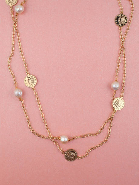 istock Two women`s gold necklaces on shimmering pink background 1272803443