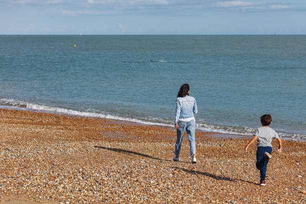 Mother with young son playing on a pretty beach in Eastbourne, UK