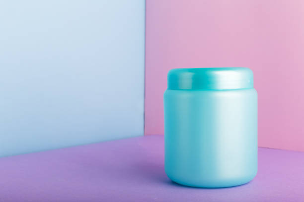 istock Blue plastic jar with mock up for cosmetic products on color pink background with Copy space. Cosmetic package for hair mask, conditioner shower gel hygiene products, homemade natural cosmetics. 1272804885