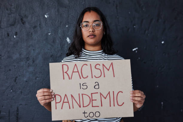 Nothing right about racism Studio shot of a young woman protesting against racism against a dark background racial equality photos stock pictures, royalty-free photos & images