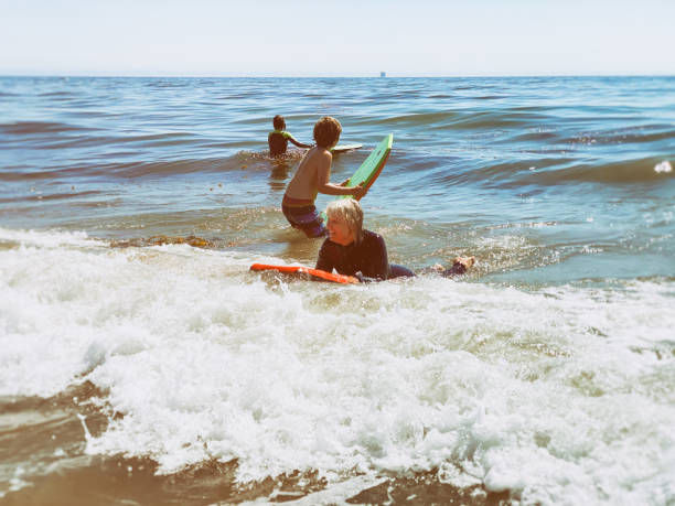 istock Grandmother boogie boards in the ocean for the first time 1272811085