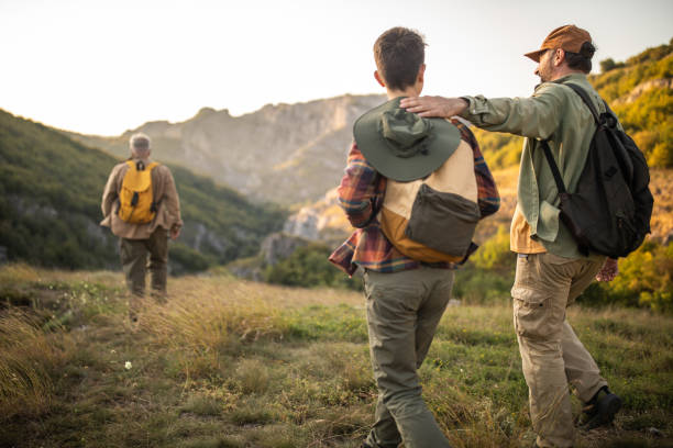 istock Multi-generation family with backpacks hiking together on mountain during sunset 1272821027