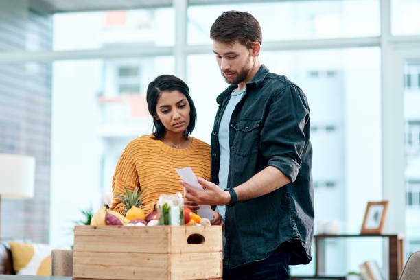 When keeping healthy comes at a cost Shot of a young couple going through their receipts at home after buying groceries inflation stock pictures, royalty-free photos & images