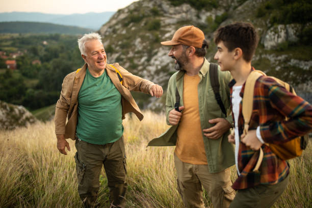 istock Multi-generation family with backpacks hiking together on mountain during sunset 1272821861