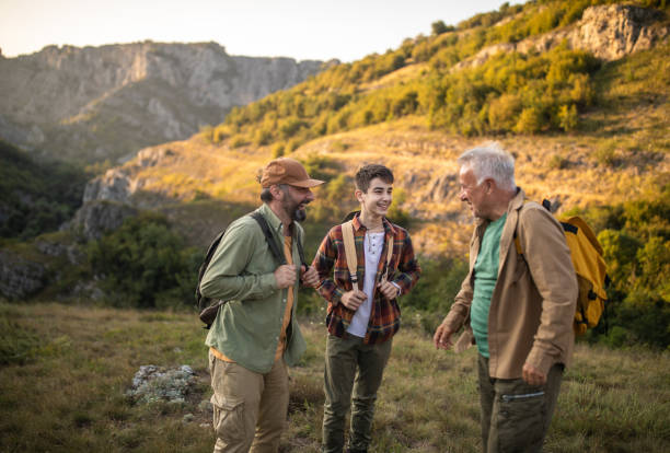 istock Multi-generation family with backpacks hiking together on mountain during sunset 1272821931