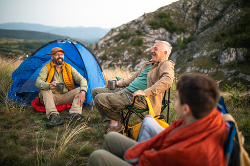 Grandfather, father and son enjoying quality time together during camping on mountain