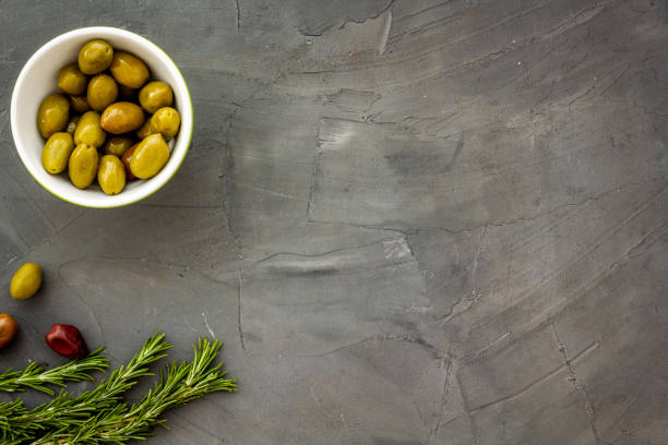 istock Mixed olives in bowl and rosemary branches top view space for text 1272822158
