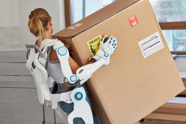 Professional female home mover in powered exoskeleton. Carrying heavy box Moving to new apartment. Close up powered exoskeleton photos stock pictures, royalty-free photos & images