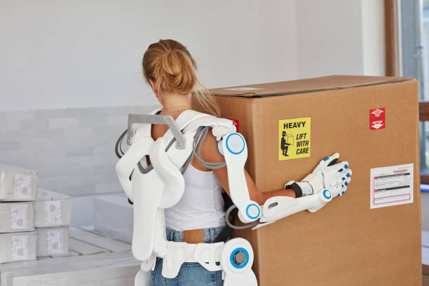 Professional female home mover in powered exoskeleton. Carrying heavy box Moving to new apartment. Close up powered exoskeleton photos stock pictures, royalty-free photos & images