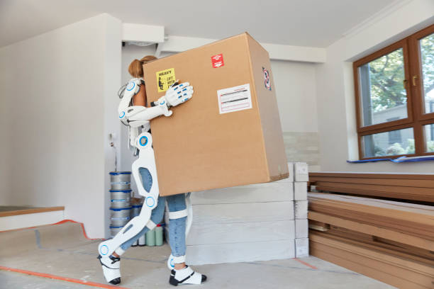Professional female home mover in powered exoskeleton. Carrying heavy box
