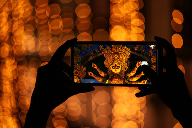 Durga Puja Festival Celebration Hand holding mobile phone and taking photos of Goddess Durga idol at a pandal. Durga Puja memories of 2019 is the biggest religious festival of Hinduism and Bengali Community. durga stock pictures, royalty-free photos & images