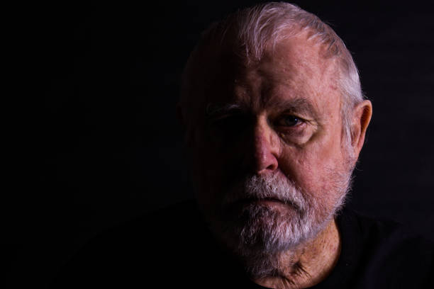 istock Old Senior Man Half Face Against Black Background 1272826720