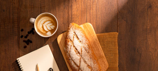istock Cup of hot coffee with bread on wood background 1272826726