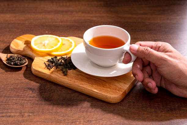 istock Cup of freshly tea with yellow lemon on black 1272828247