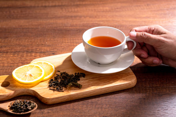 istock Cup of freshly tea with yellow lemon on black 1272828288