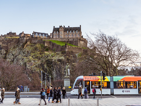 Edinburgh, Scotland - A tram passing as pedestrians walk on Princes Street in central Edinburgh, with the castle on the skyline.