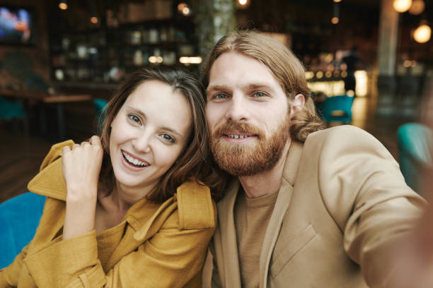istock Displeased young bearded man sitting in modern cafe and waiting for answer while calling by cellphone 1272831486