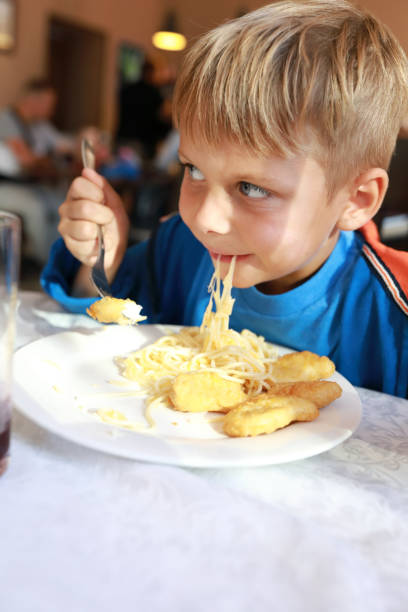 istock Child eating spaghetti with nuggets 1272837124
