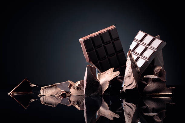istock A broken chocolate bar and pieces of dark chocolate on a black reflective background. 1272837418