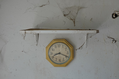 Old dusty clock and wall with cobweb in abandoned house.