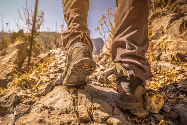 Close-up shot in nature. Feet of someone walking with a walking boot and walking cane. Taken while in motion. The shoe has many features such as vibratory sole, goretex, wrist grip