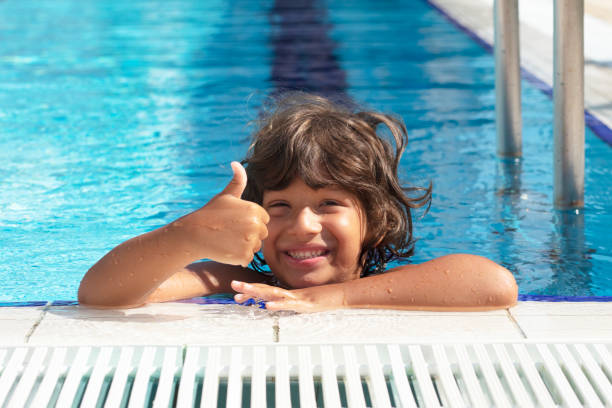 istock Happy Smiling Boy Looking At Camera In Swimming Pool 1272841835