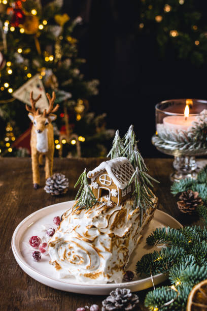 istock Christmas dessert, meringue roll decorated with gingerbread house, bokeh lights 1272843023