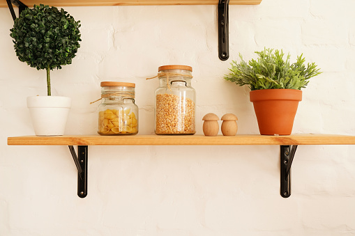 kitchen shelf with food - jars of cereals with green plant