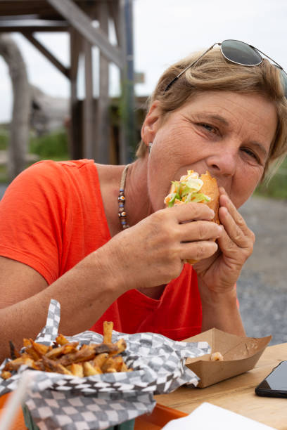 istock Mature Woman tasting Shrimp Sandwich 1272845519