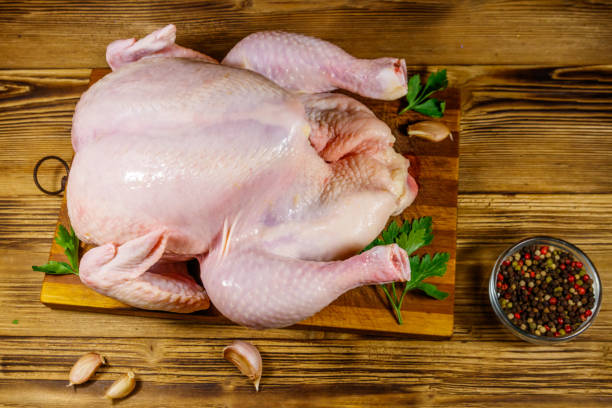 istock Raw whole chicken with spices on a wooden table. Top view 1272846107