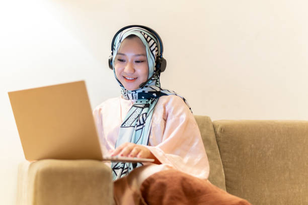 istock Young asian lady wearing hijab using computer for conference call at sofa 1272848873