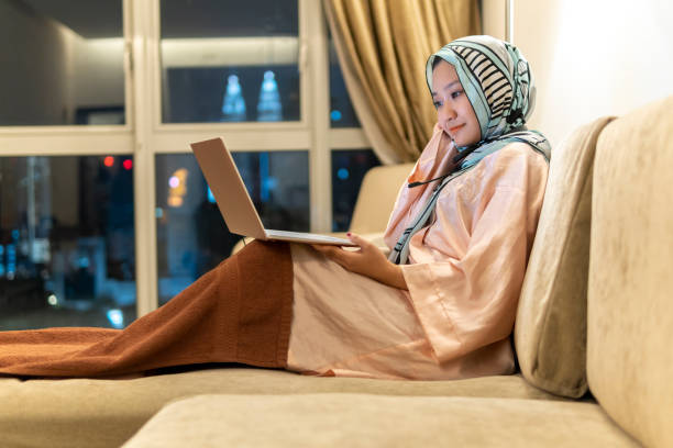 istock Young asian lady wearing hijab using computer for conference call at sofa 1272848882