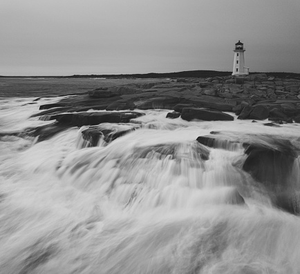 Low level drone view of Peggy's Cove Lighthouse in evening light with heavy surf.