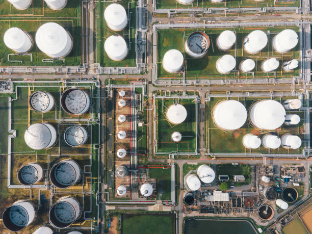 aerial view morning time of petro chemical plant and oil refinery, power plant working with crude oil storage tank at sunrise near mountain green environment concept - environmental damage power station factory smoke stack imagens e fotografias de stock