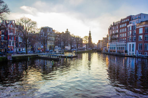 Idyllic view on Amsterdam : water in canals and  sunset sky and awe medieval architecture. Winter in Netherlandes.