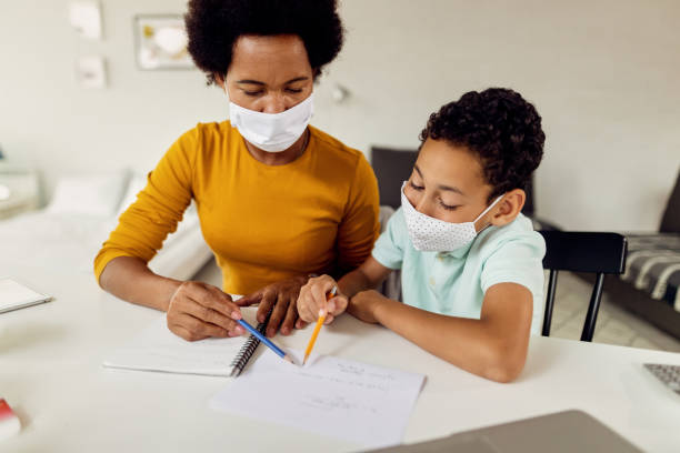 istock African American mother and son doing homework and wearing protective face masks. 1272853499