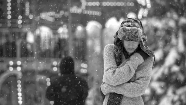 Photo of Winter depressed sad girl lonely walking alone with falling snowflakes