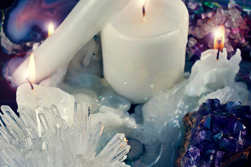 Burning candles with amethyst and quartz crystals and agate stone.