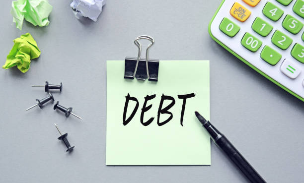istock Lettering Debt on a sheet of notes. Lettering content has implications for business content and finance. 1272860470