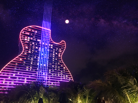 Hollywood - Fort Lauderdale, FL, USA - September 11, 2020: Colorful exterior general night view of the Hard Rock Cafe & Casino guitar shaped hotel, the first guitar shaped hotel in the world. All nights the building turn on millions of lights, showing a spectacular light show on their facade.\n\nThis building is just one hour driving from Miami / Miami Beach, and two hours driving from Orlando and Disney's Theme Parks.