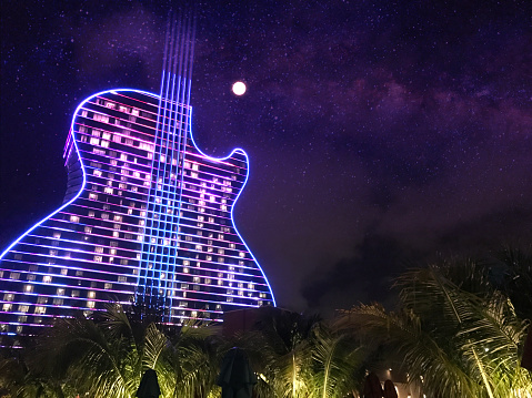 Hollywood - Fort Lauderdale, FL, USA - September 11, 2020: Colorful exterior general night view of the Hard Rock Cafe & Casino guitar shaped hotel, the first guitar shaped hotel in the world. All nights the building turn on millions of lights, showing a spectacular light show on their facade.\n\nThis building is just one hour driving from Miami / Miami Beach, and two hours driving from Orlando and Disney's Theme Parks.